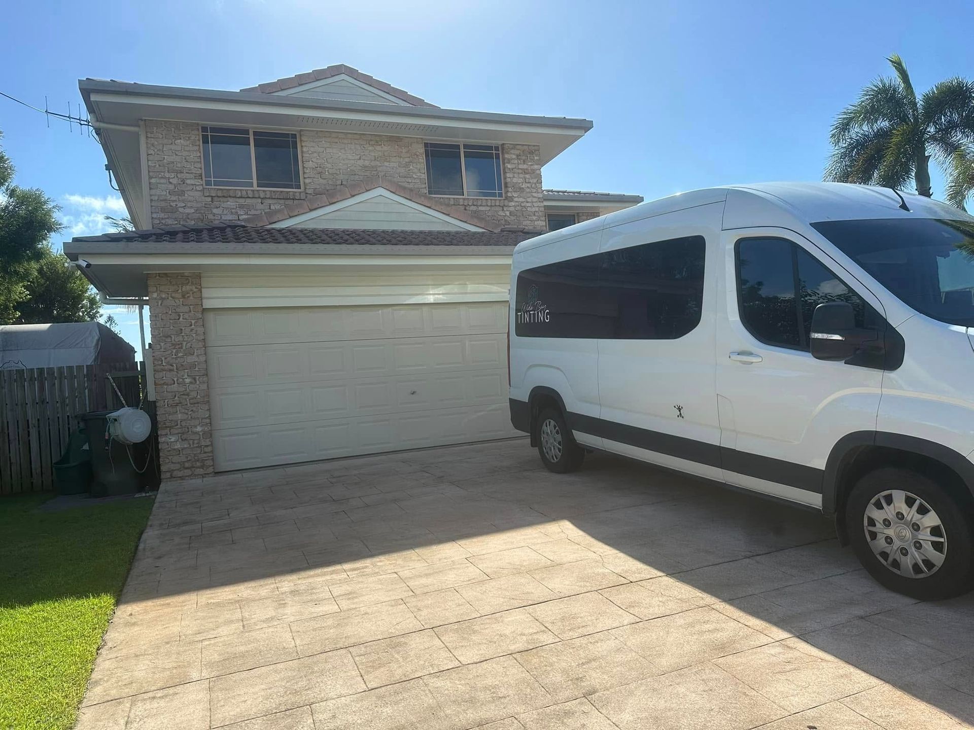 White van parked in front of a two-story brick house with a closed garage door — Wide Bay Tinting in Kensington, QLD