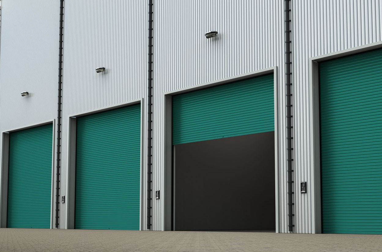 We Box Self Storage Uma fileira de portas de garagem verdes em um prédio.