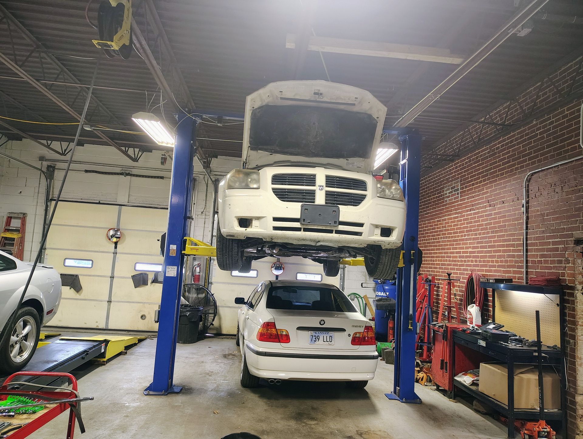 Car on a lift in a garage with another car underneath | MJ Auto Repair