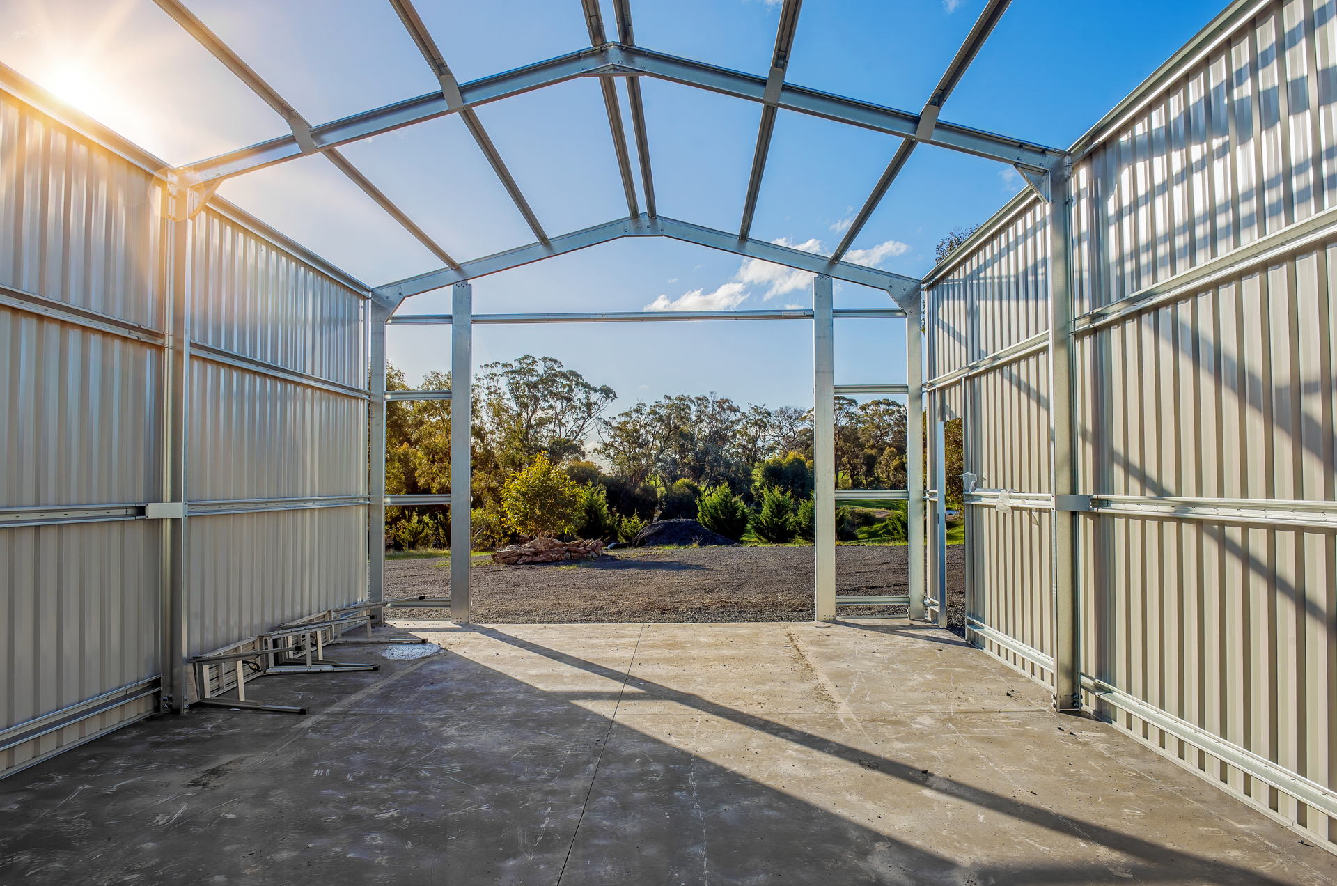 Metal frame shed under construction, with open front and blue sky backdrop.