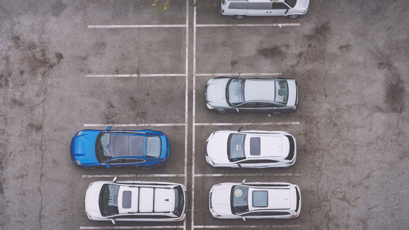 An aerial view of five cars parked in designated spots within an outdoor parking lot.