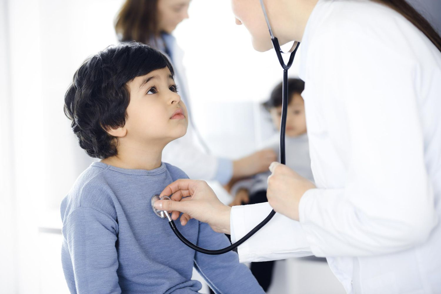 A doctor is listening to a child 's heart with a stethoscope.