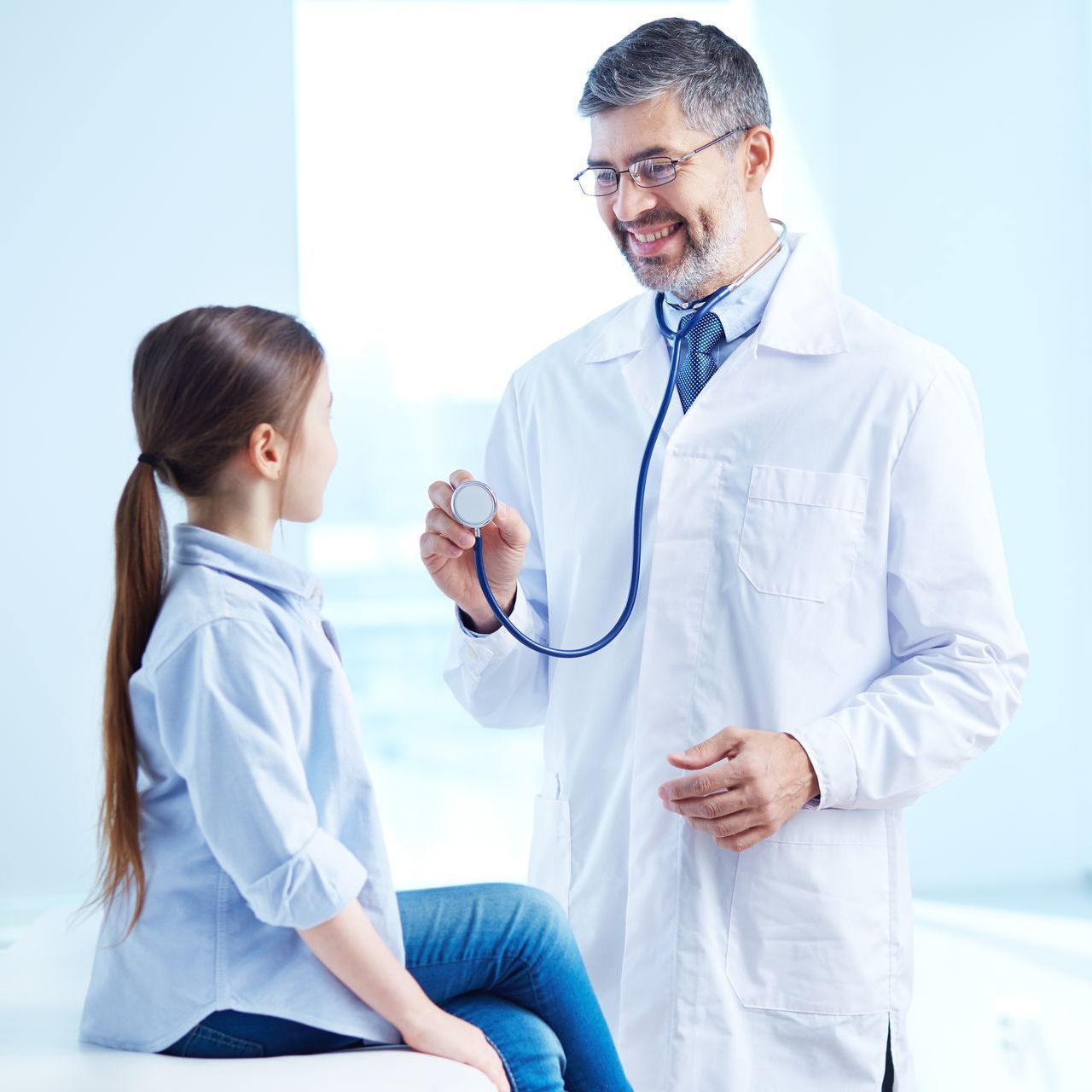 A doctor is examining a young girl with a stethoscope.