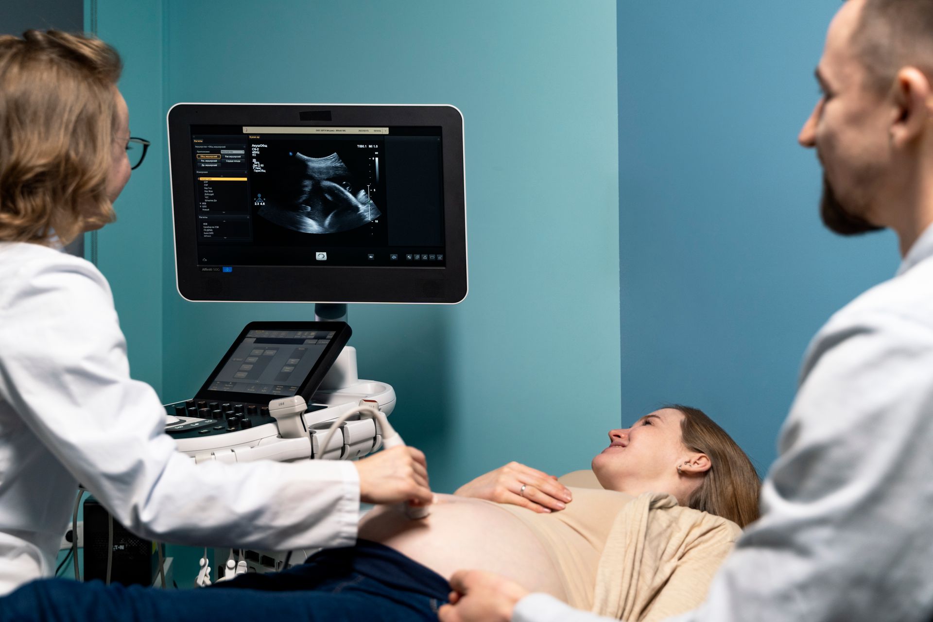 A pregnant woman is getting an ultrasound from a doctor.