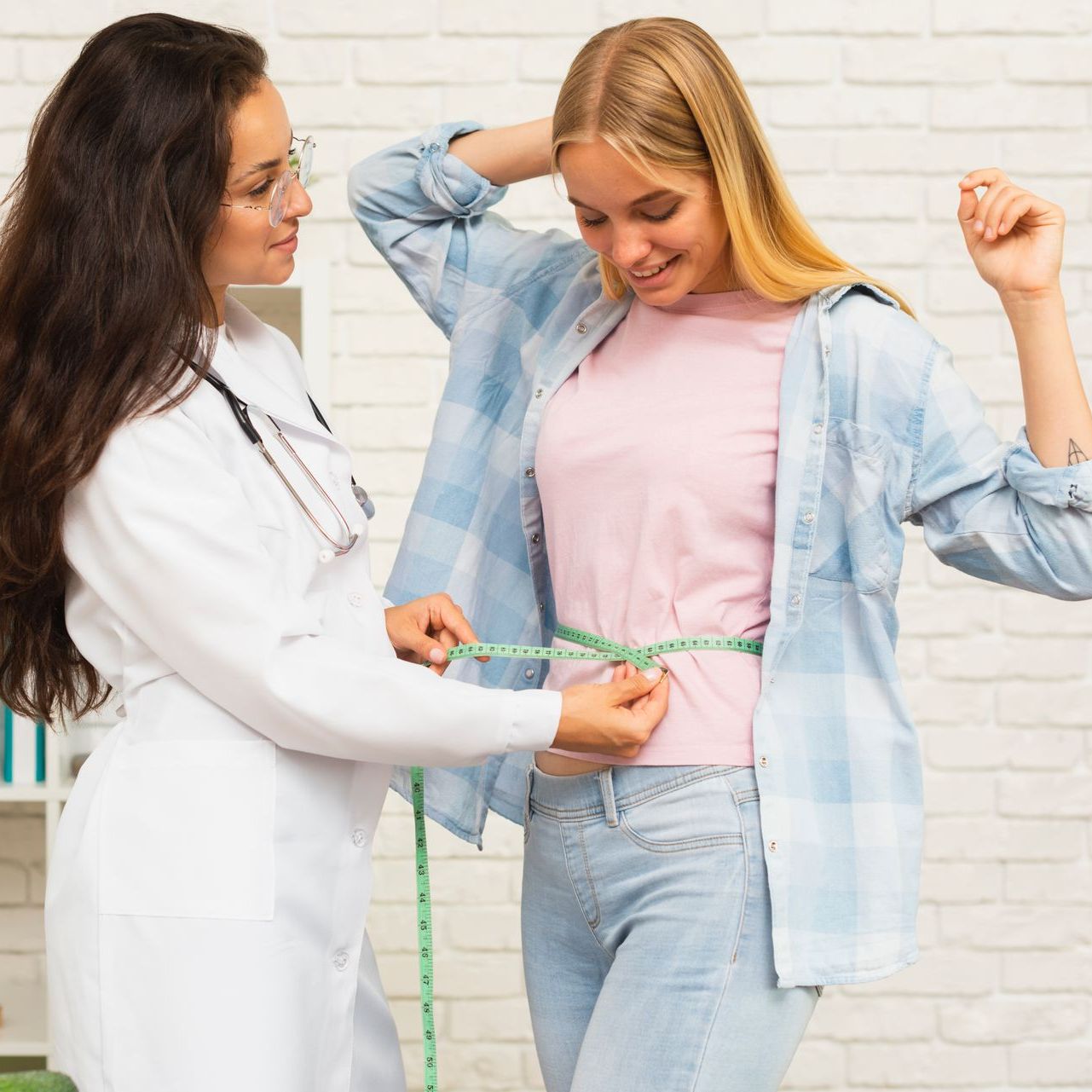 A doctor is measuring a woman 's waist with a tape measure.