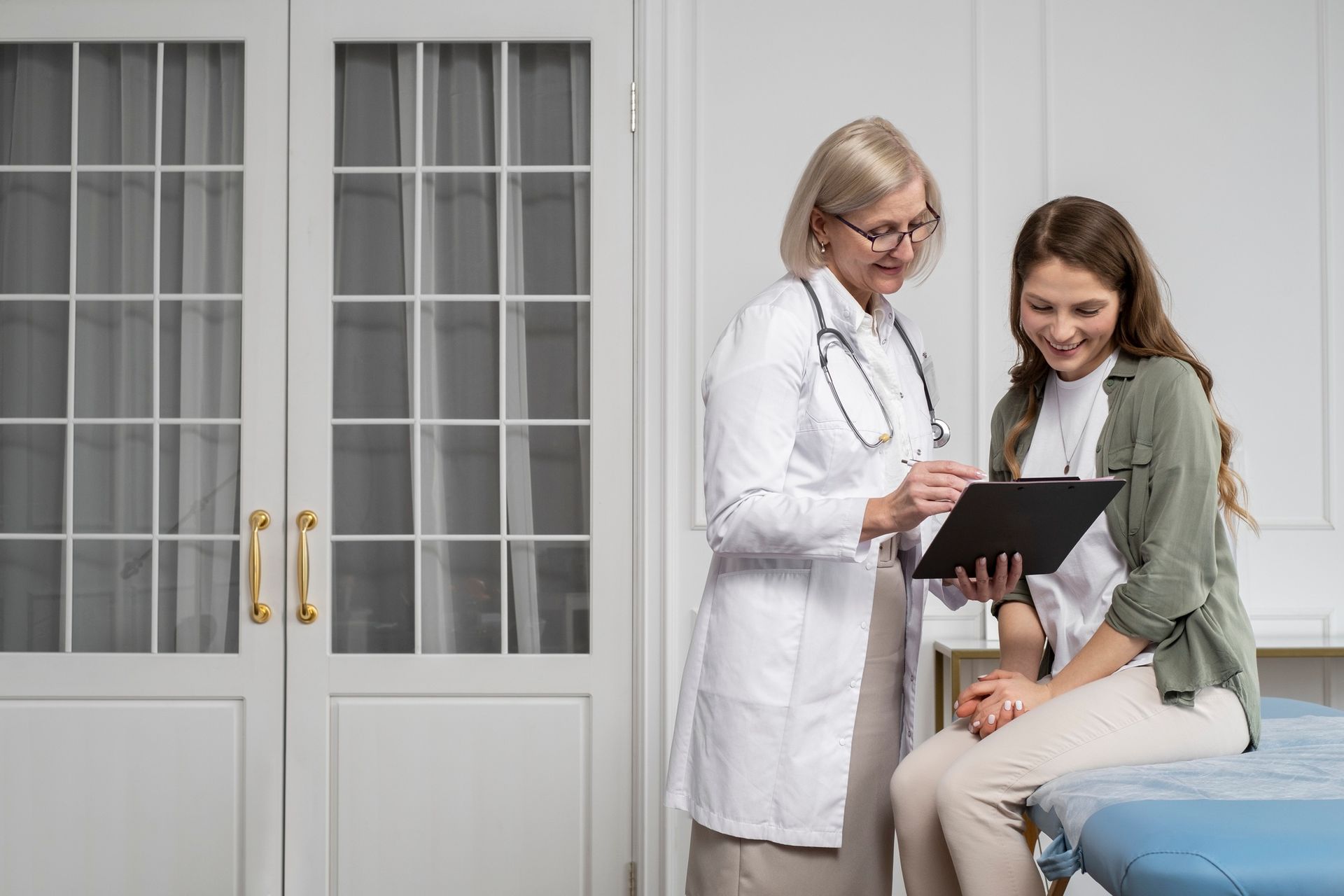 A doctor is talking to a patient who is sitting on a bed.