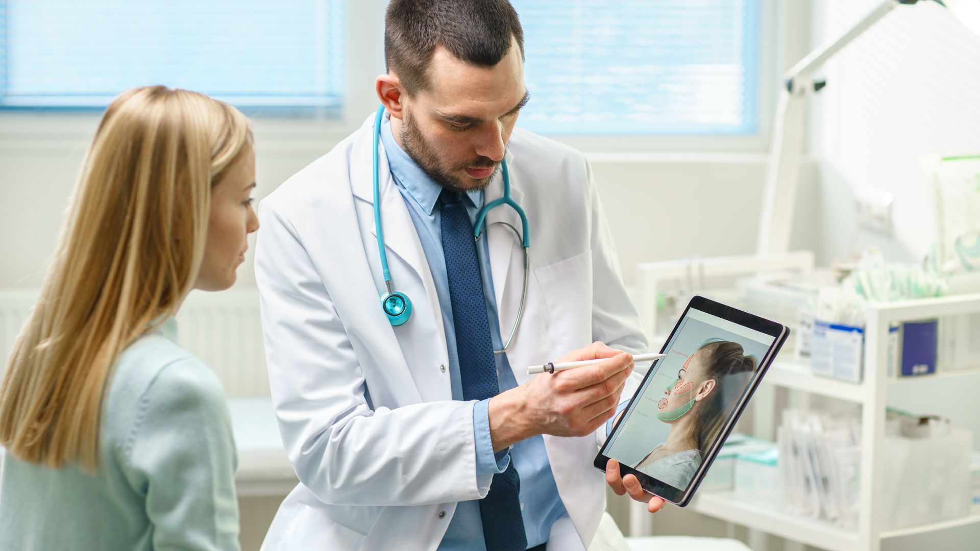 A doctor is talking to a patient while looking at a tablet.
