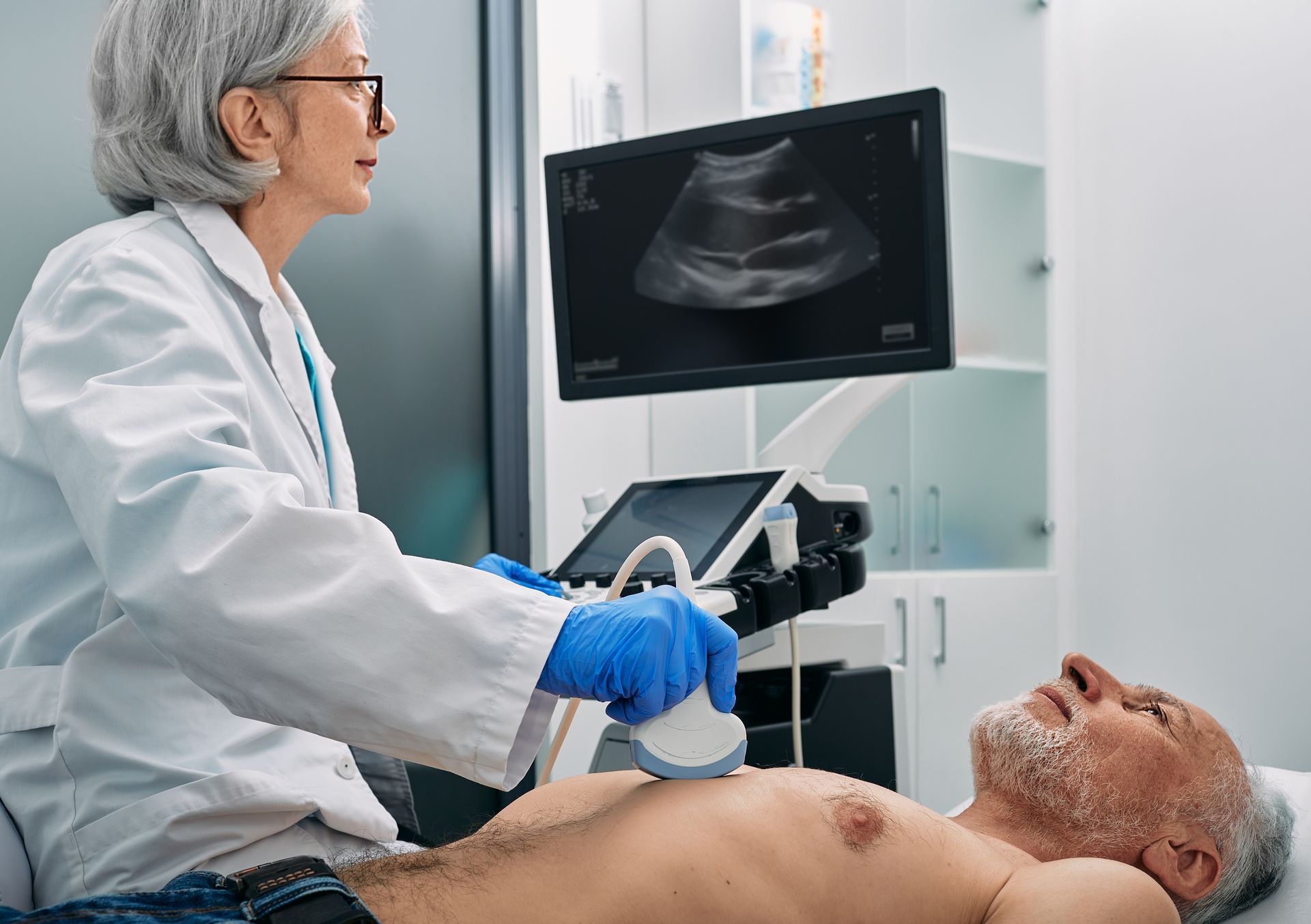 A doctor is examining a man 's chest with an ultrasound machine.