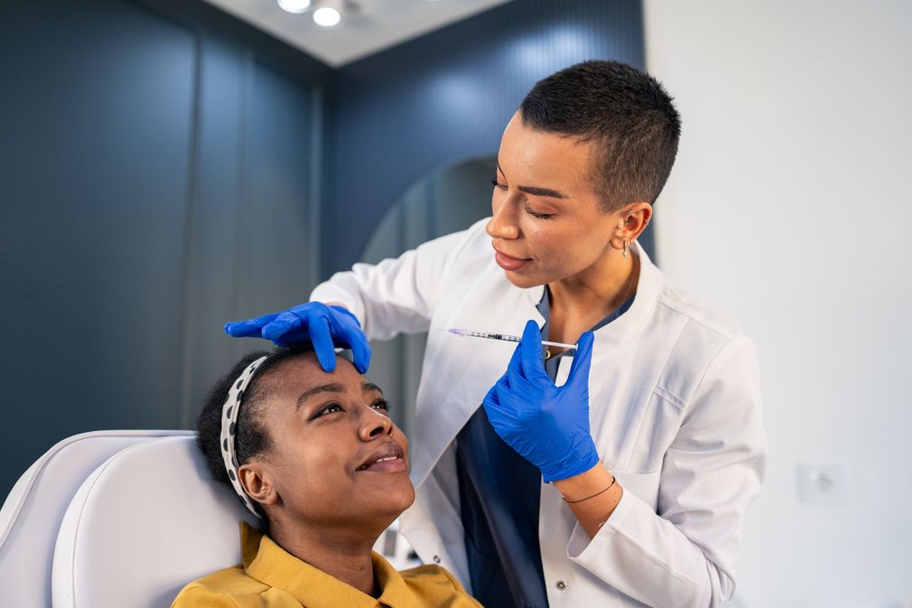 Dentist examining a patient’s mouth with blue-gloved hands in a bright clinic