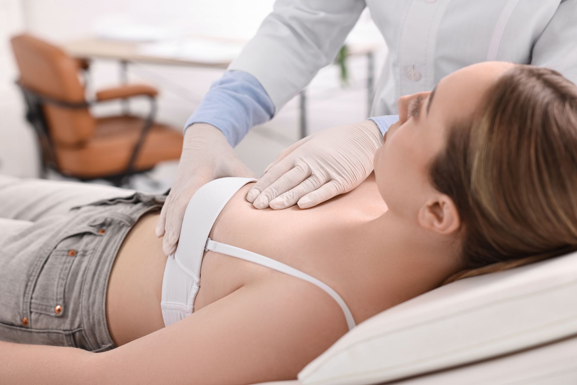 A woman is laying on a bed while a doctor examines her chest.