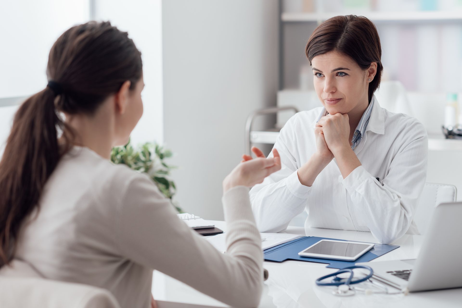 A woman is sitting at a table talking to a doctor.