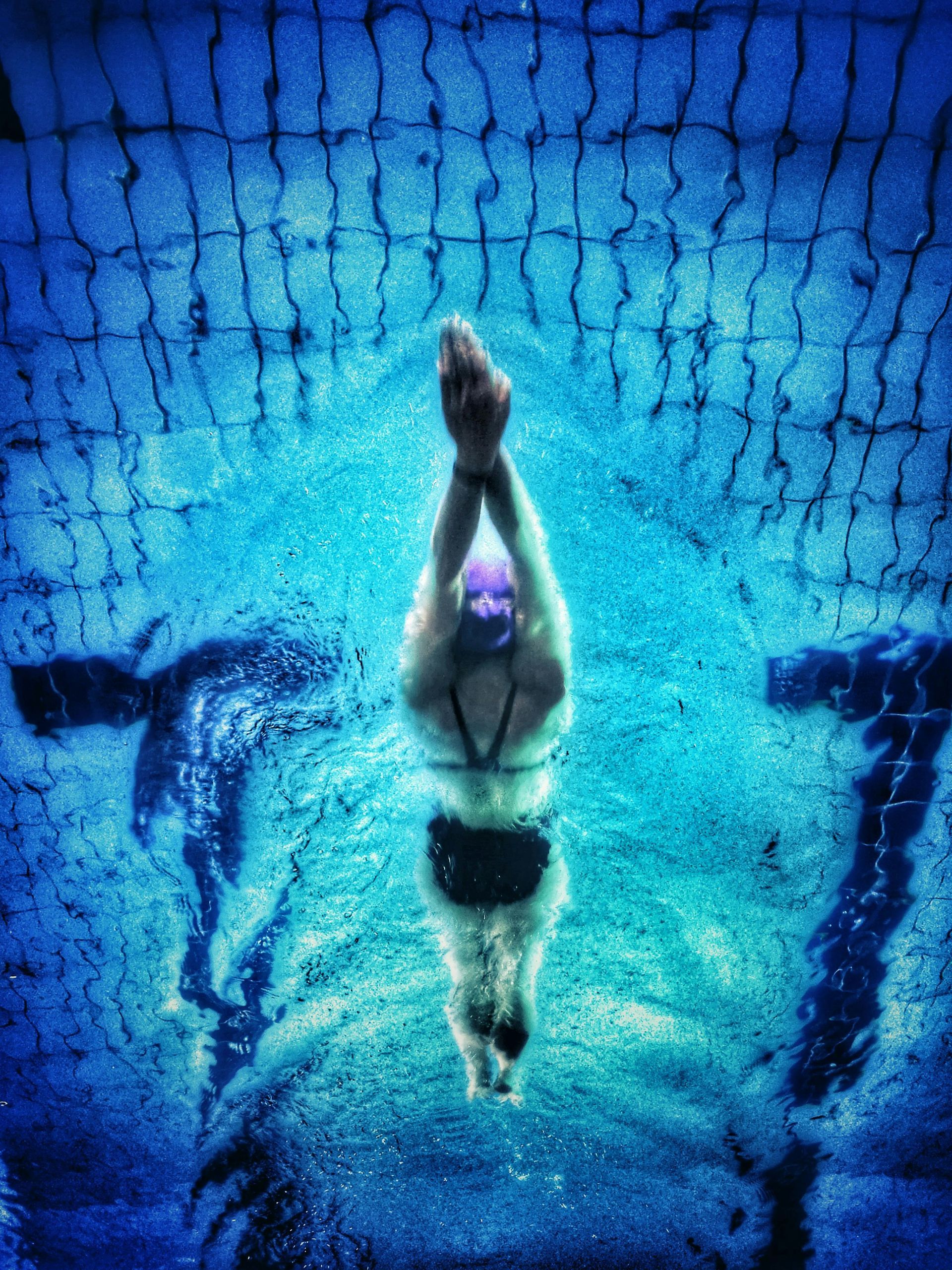 A woman is swimming underwater in a pool.