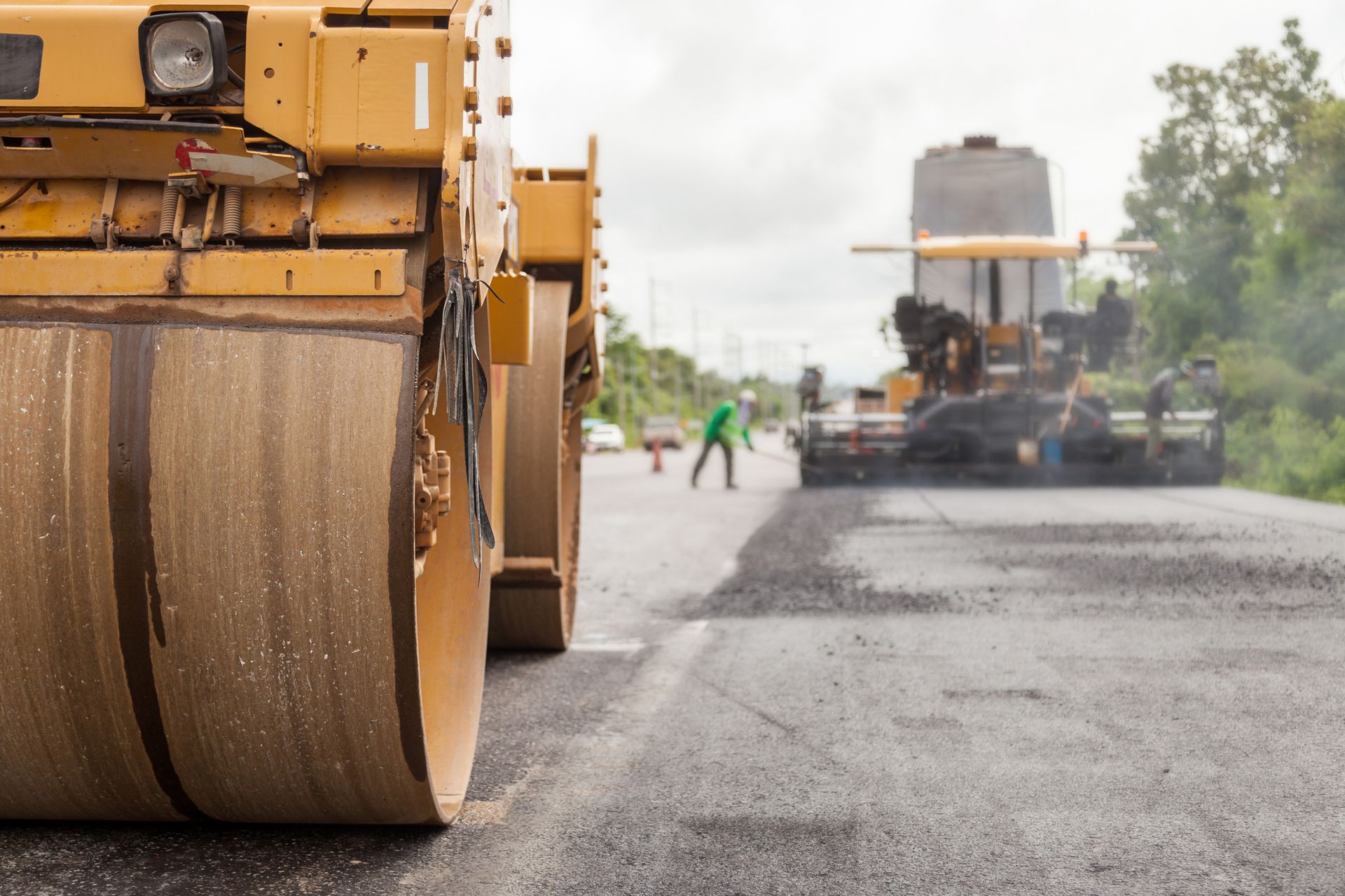 Road construction works with roller compactor machine and asphalt finisher. | Dependable Paving Co