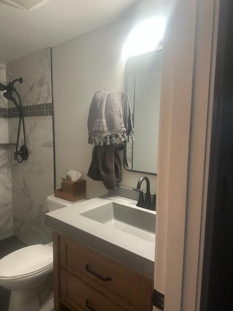 Bathroom with marble shower, wooden vanity, sink, mirror, and towel rack.