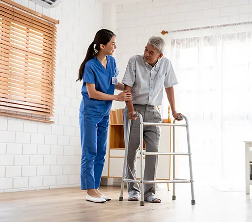 Caregiver assists senior man using a walker in a room with a window, white walls, and wooden blinds.