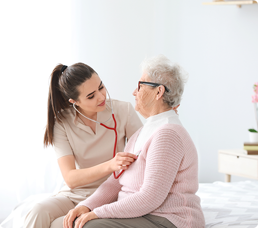 Nurse listens to a senior patient's chest with a stethoscope in a bedroom.