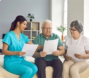 Nurse showing documents to senior couple. They are seated in a room, reviewing papers.