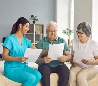 Nurse showing documents to senior couple. They are seated in a room, reviewing papers.