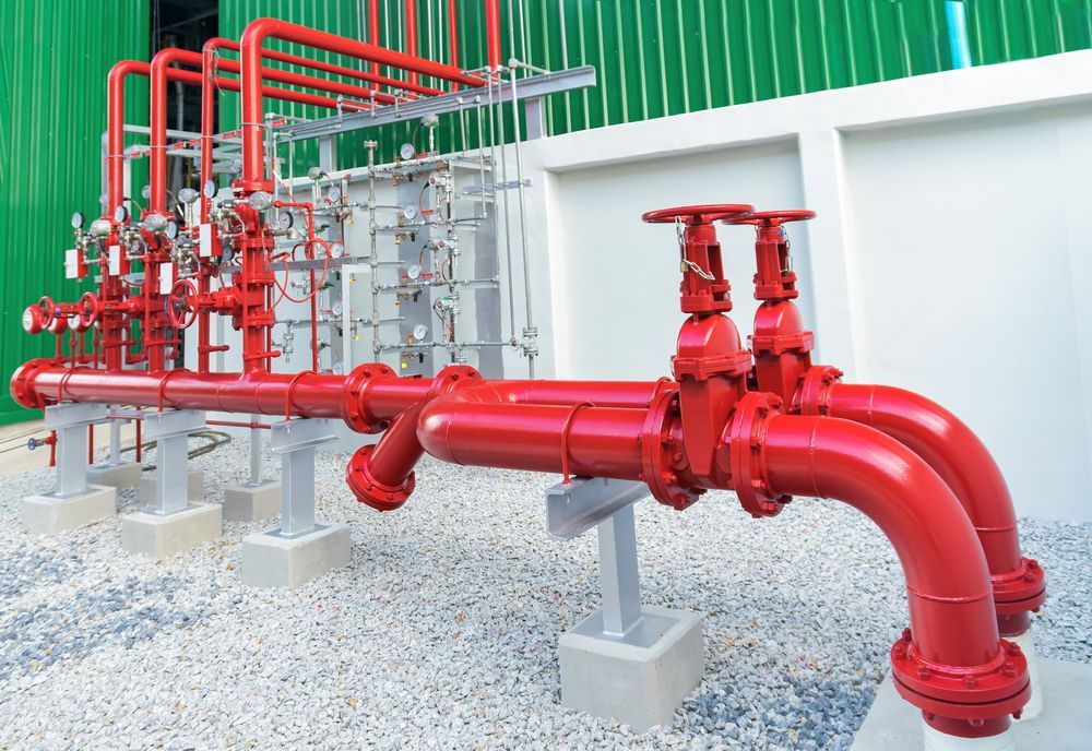 A Bunch of Red Pipes and Valves Are Sitting on Top of Gravel — The Pump Doctor In Beerwah, QLD