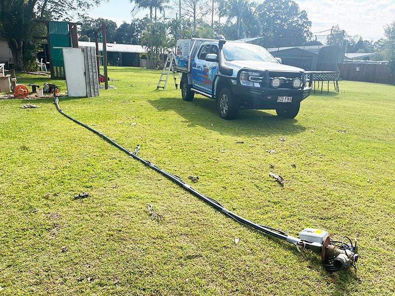 A Truck is Parked in a Grassy Field With a Hose Attached to It — The Pump Doctor In Kuluin, QLD