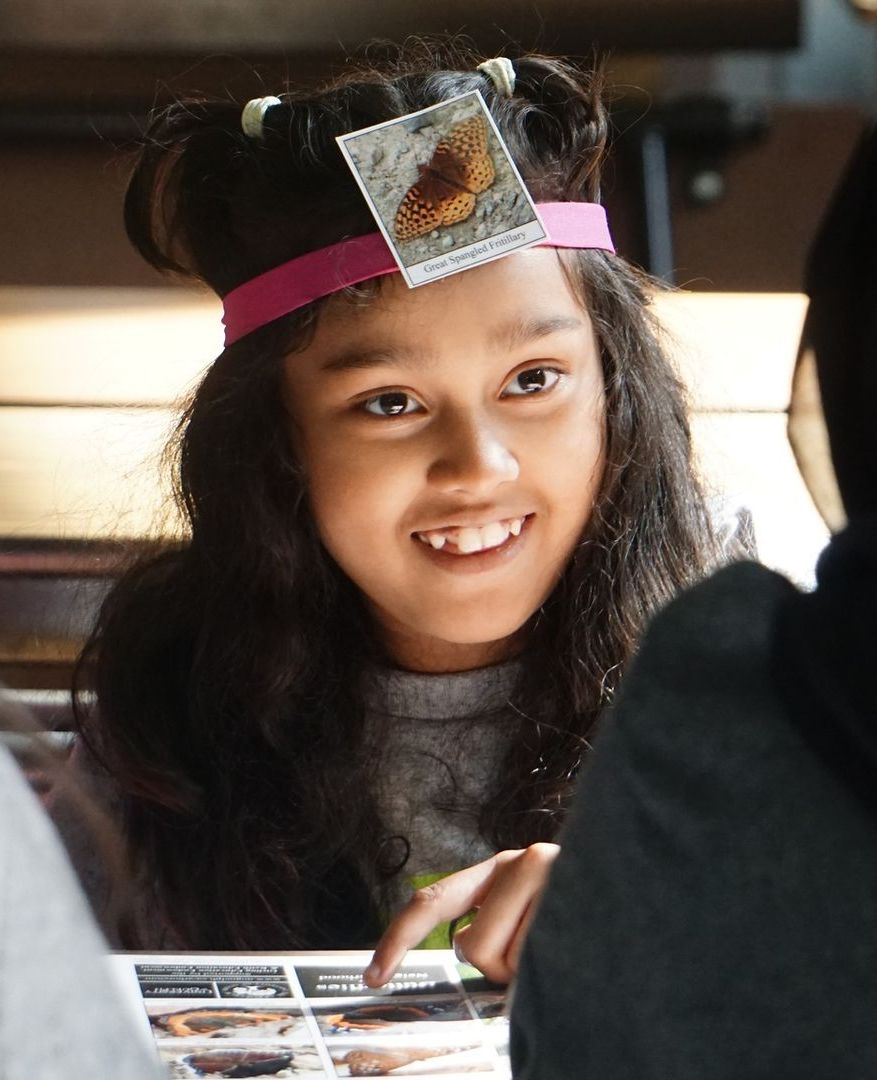 A child playing a game where you try to guess the clue that is in your headband.