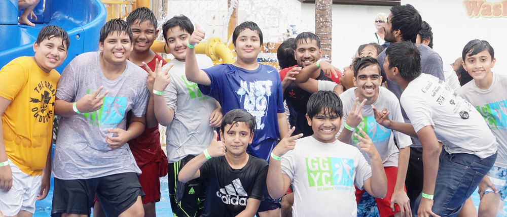 A group of young men are posing for a picture in front of a water slide.