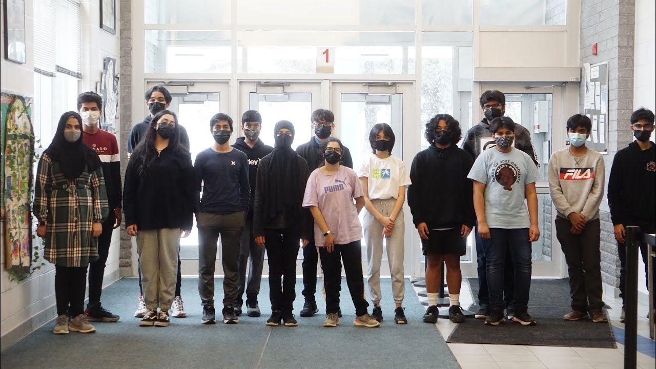 A group of people wearing face masks are standing in a hallway.