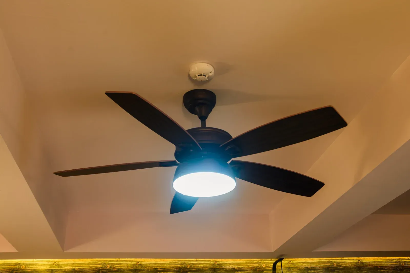 A ceiling fan with a light on it is hanging from the ceiling of a room.
