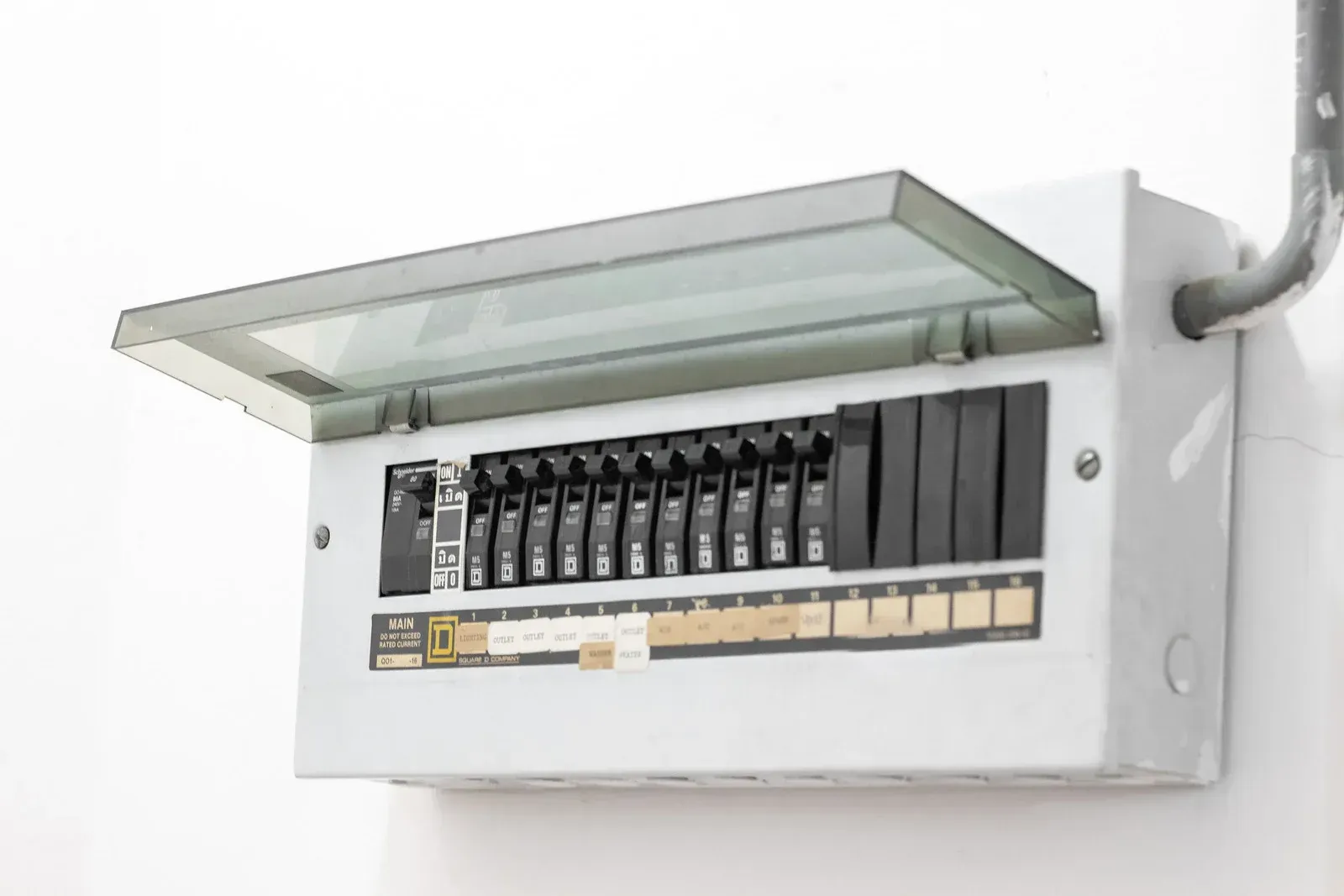 A white electrical box with the lid open on a white wall.