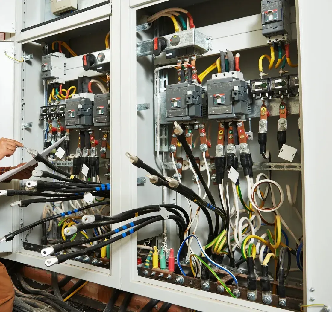 A person is working on an electrical box with lots of wires