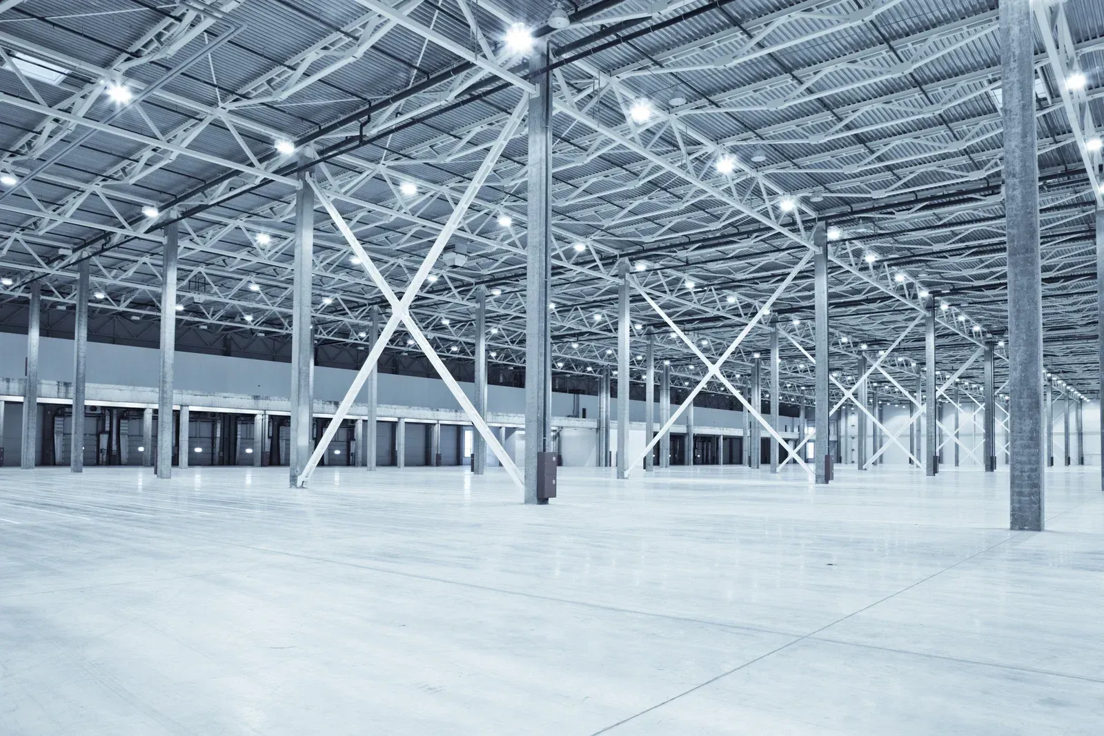 An empty warehouse with a concrete floor and a metal structure.