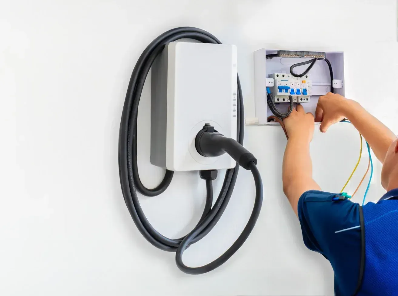 A man is installing an electric car charger on a wall.