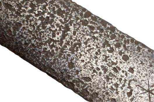 Close-up of a weathered, metallic object with a mottled, irregular texture of dark and light gray.