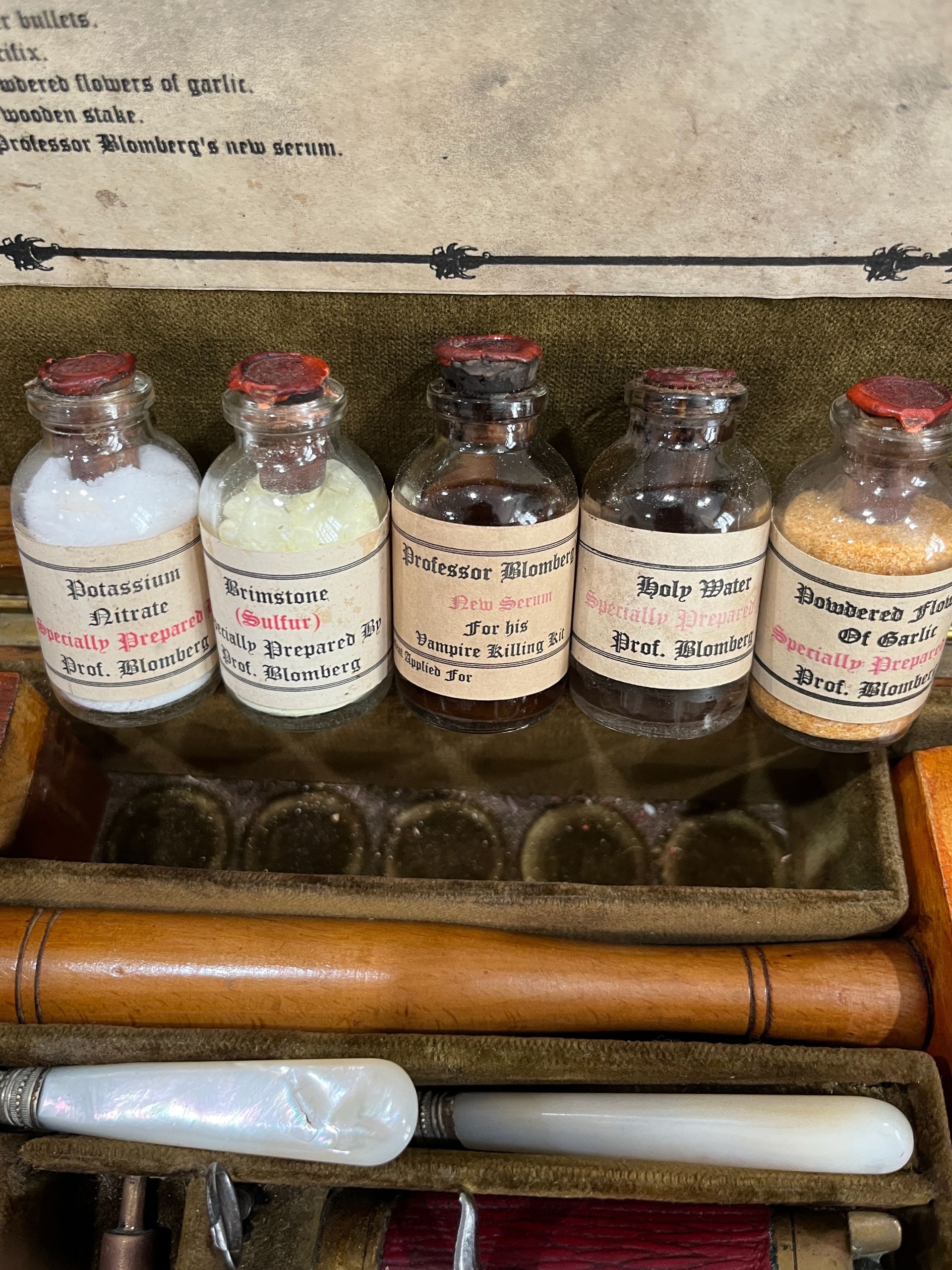 Antique wooden pistol kit, open, with various tools, including a pistol, candles, and cross.