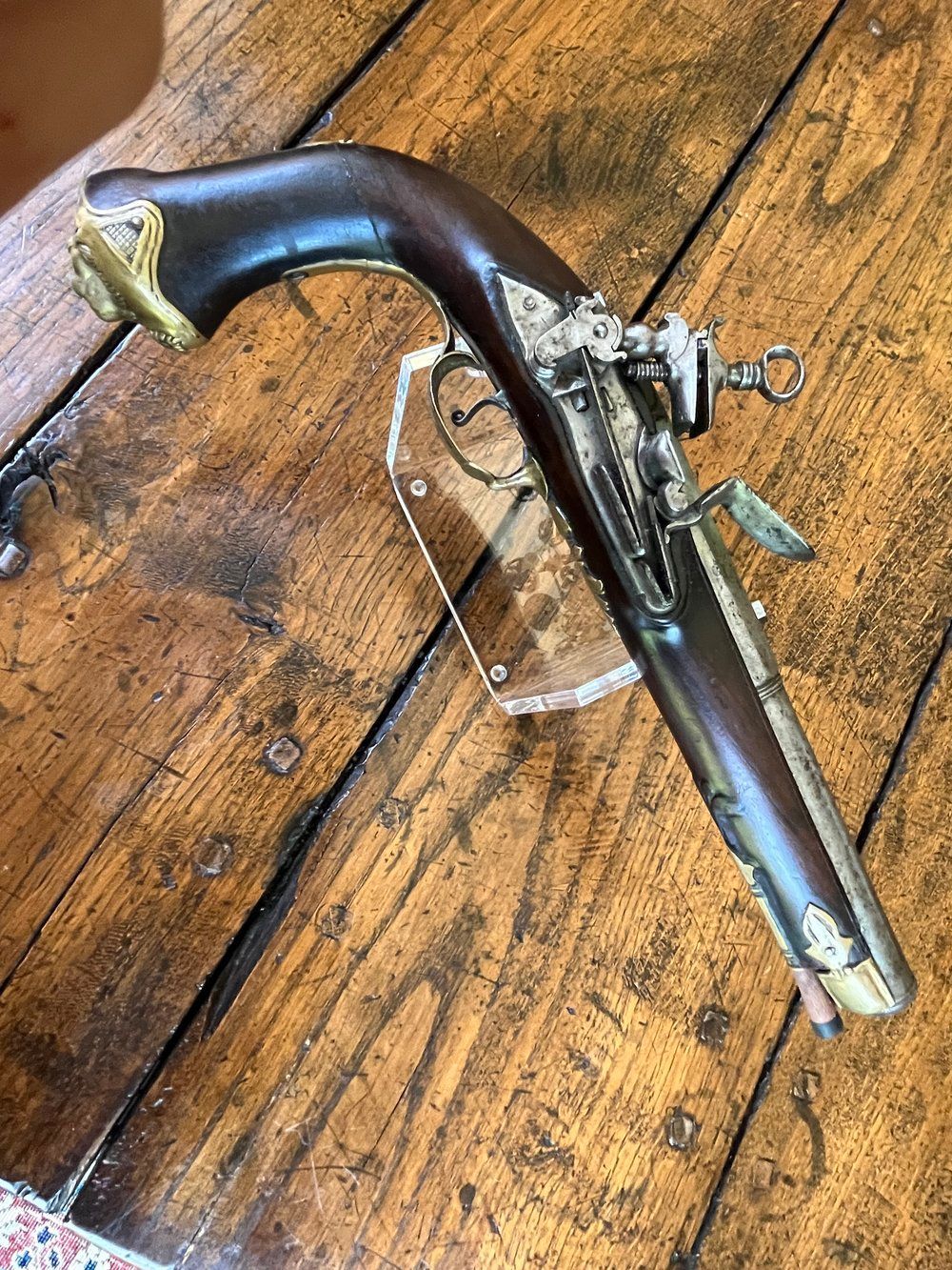 An antique pistol is sitting on a wooden table.