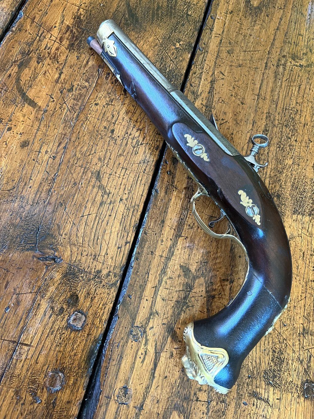 An antique pistol is sitting on a wooden table.