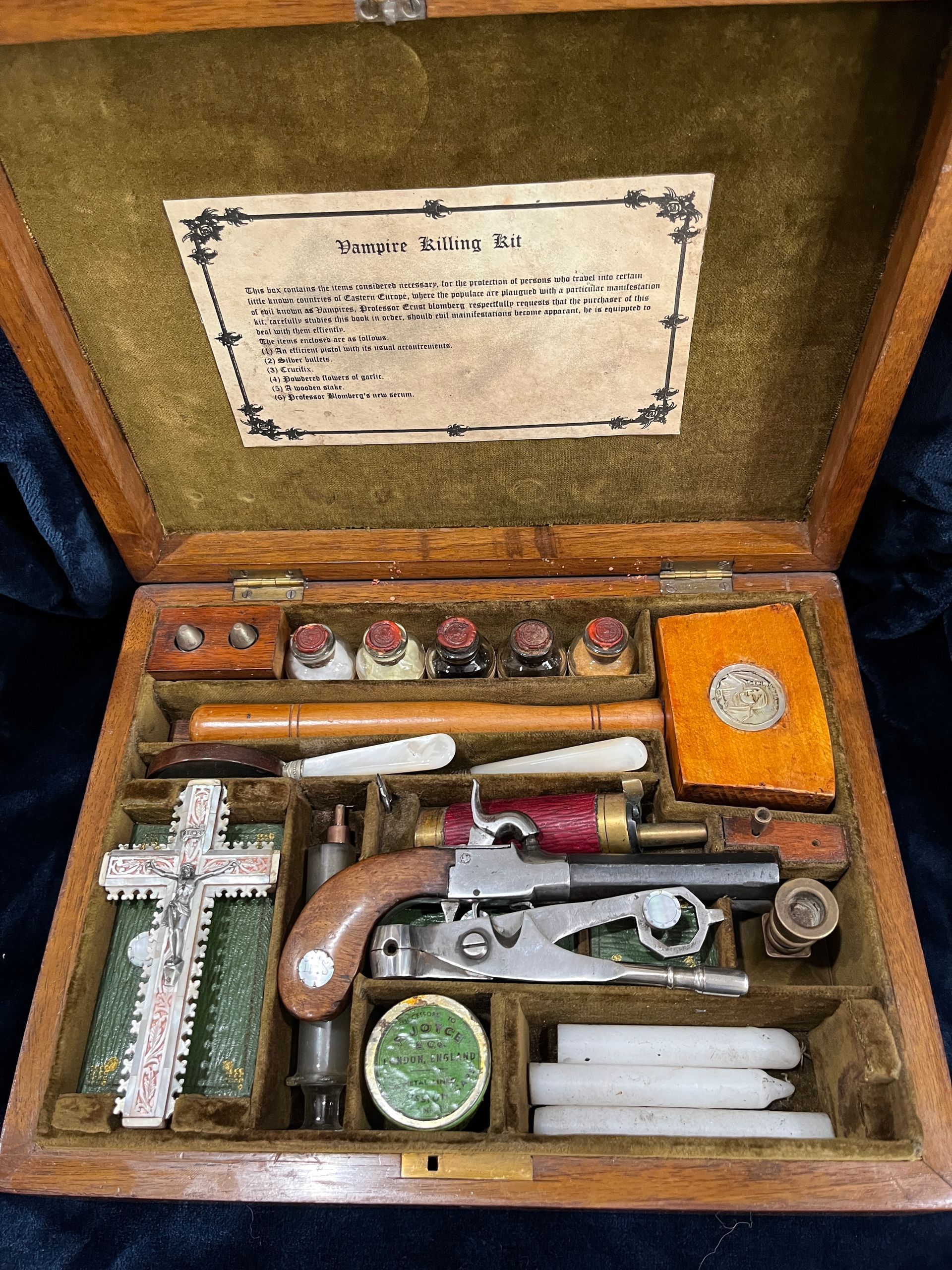 Antique wooden pistol kit, open, with various tools, including a pistol, candles, and cross.