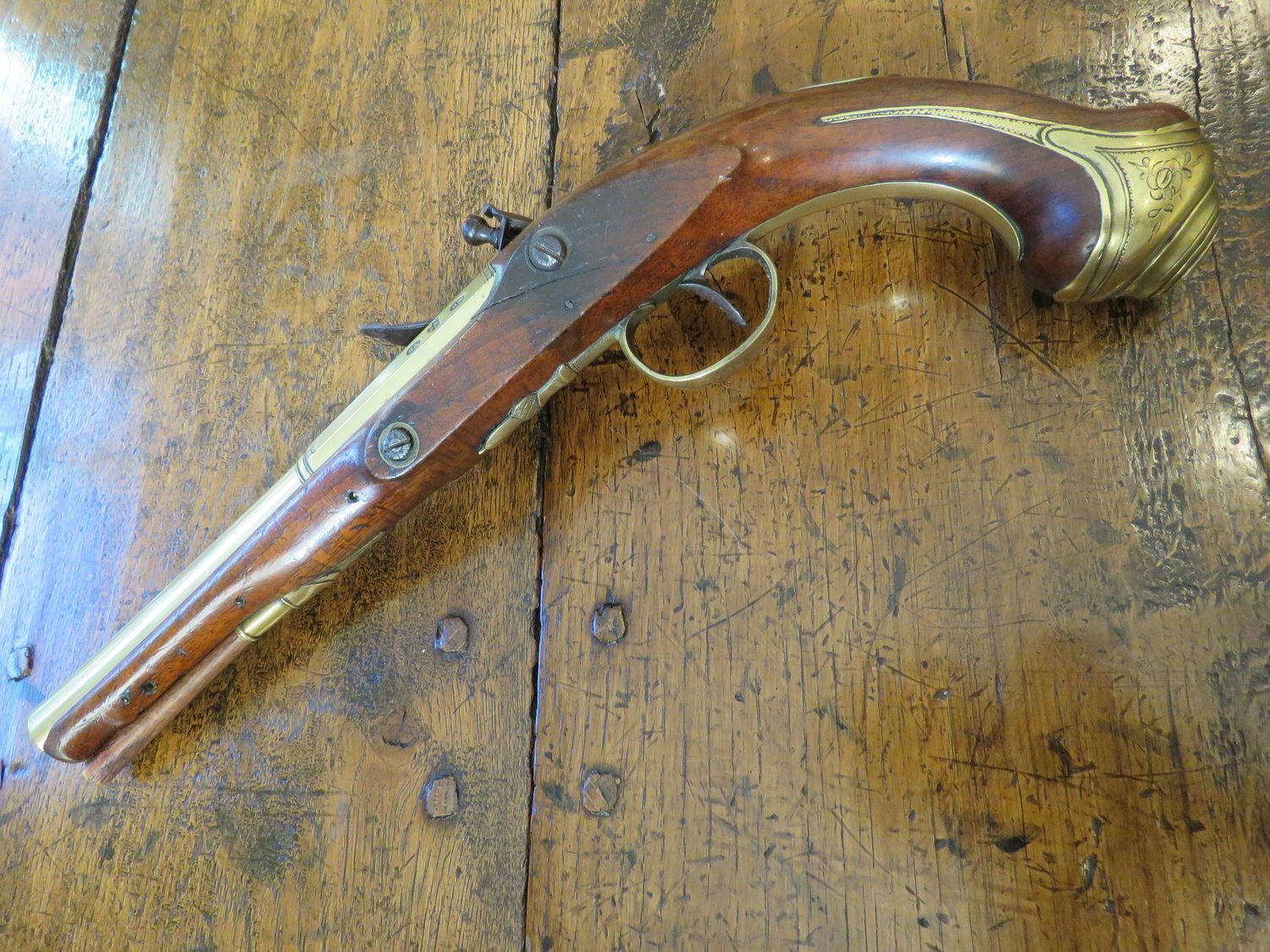 An antique flintlock pistol is sitting on a wooden table.