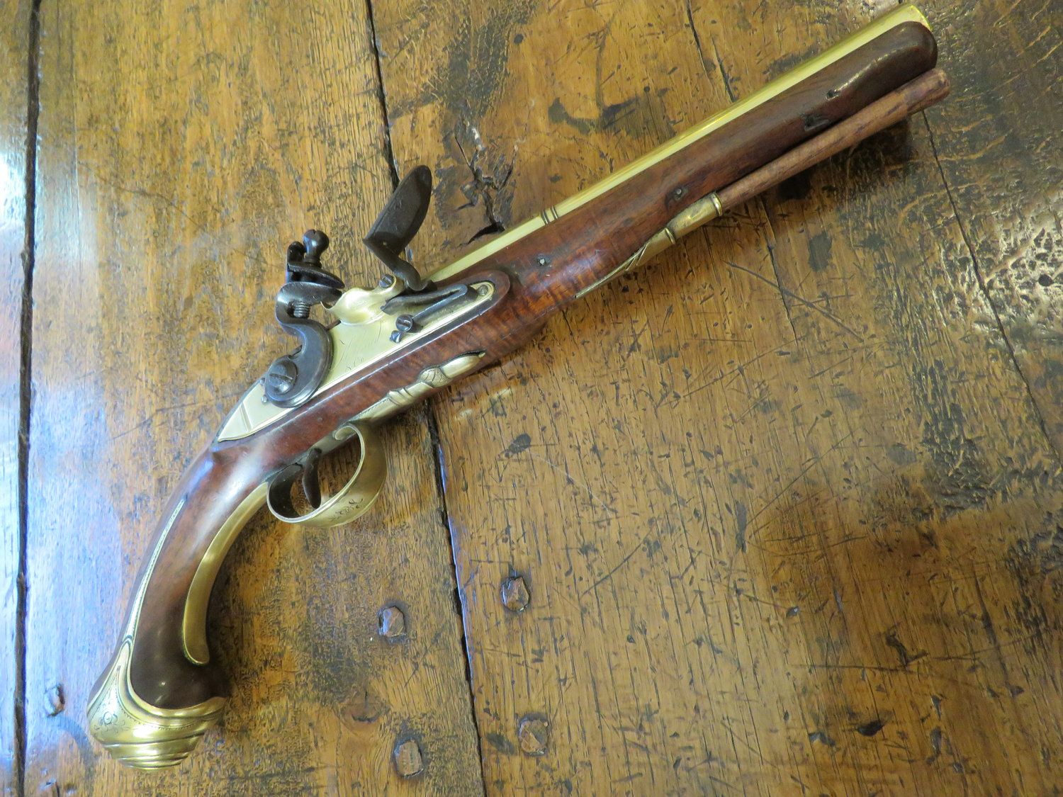 An antique flintlock pistol is sitting on a wooden table.