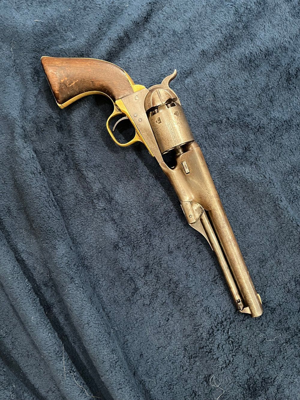An old revolver is sitting on top of a blue blanket.