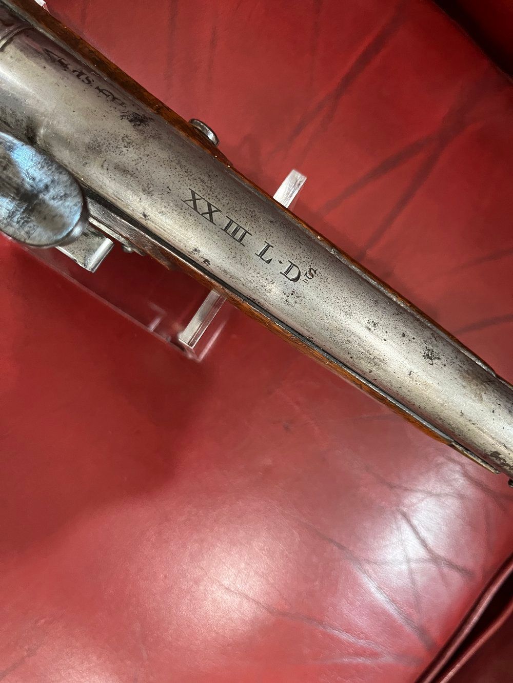 An antique flintlock pistol is sitting on a red table.