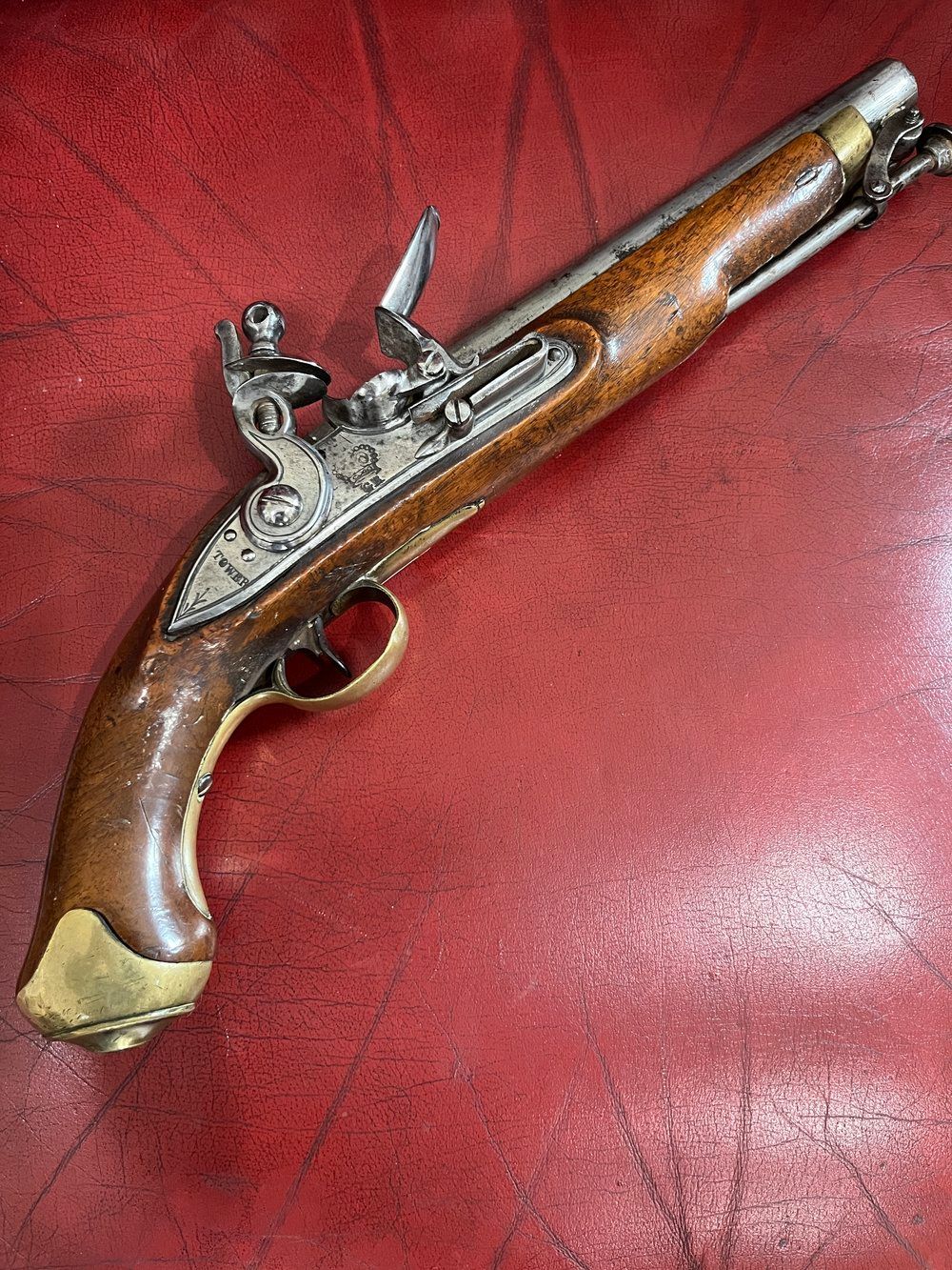 An antique flintlock pistol is sitting on a red table.