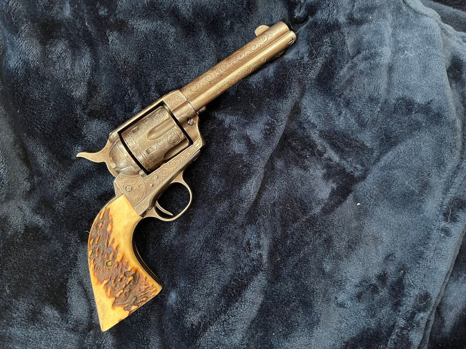 A revolver with a deer antler grip is sitting on a blue blanket.