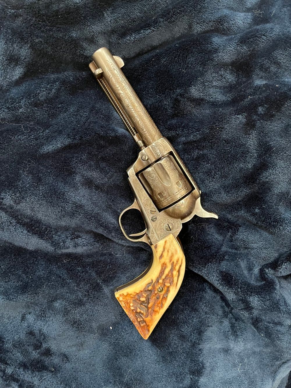 A revolver with a deer antler grip is sitting on a blue blanket.