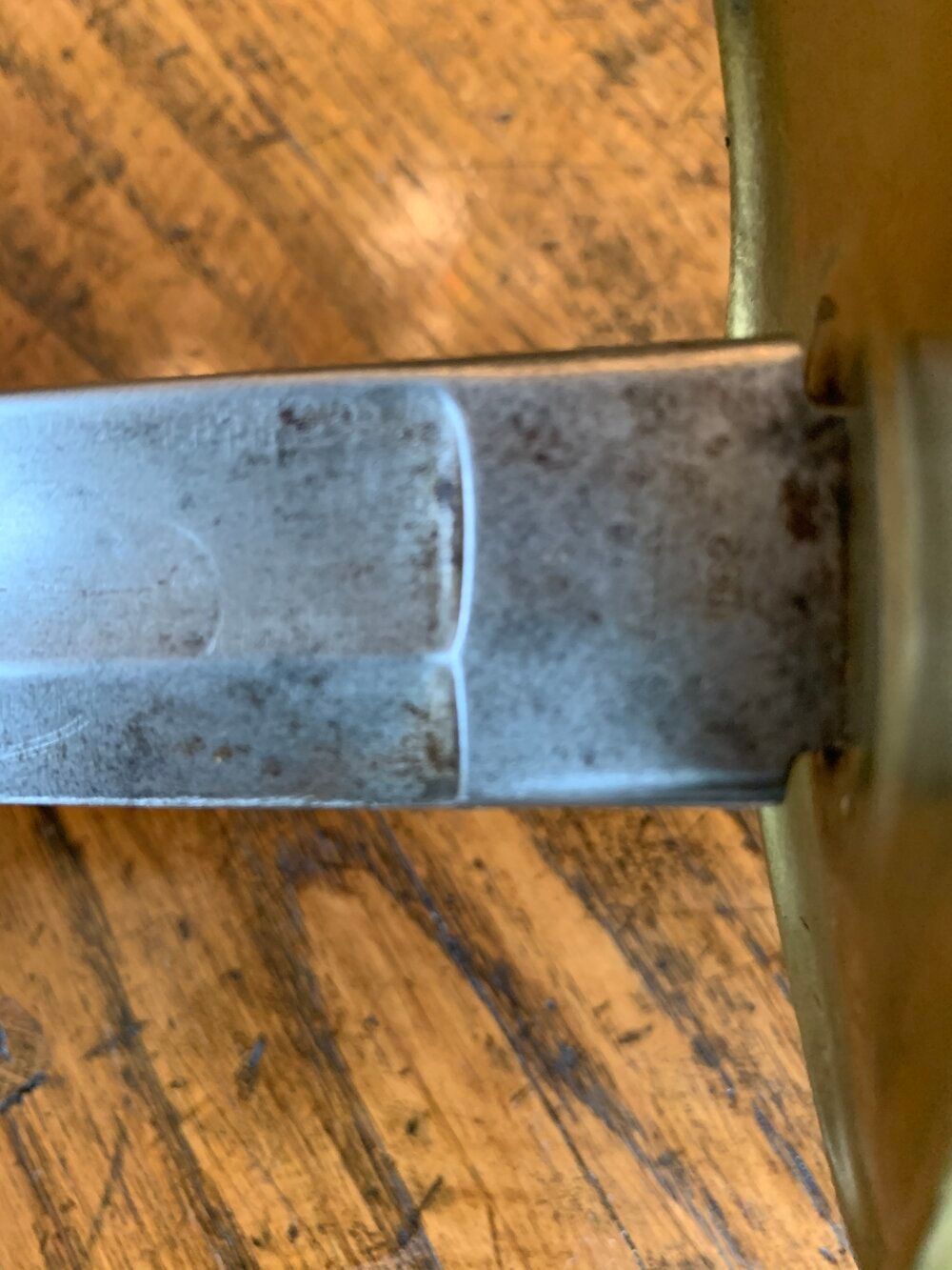 Antique sword with a wooden handle and scabbard lying on a wooden floor.