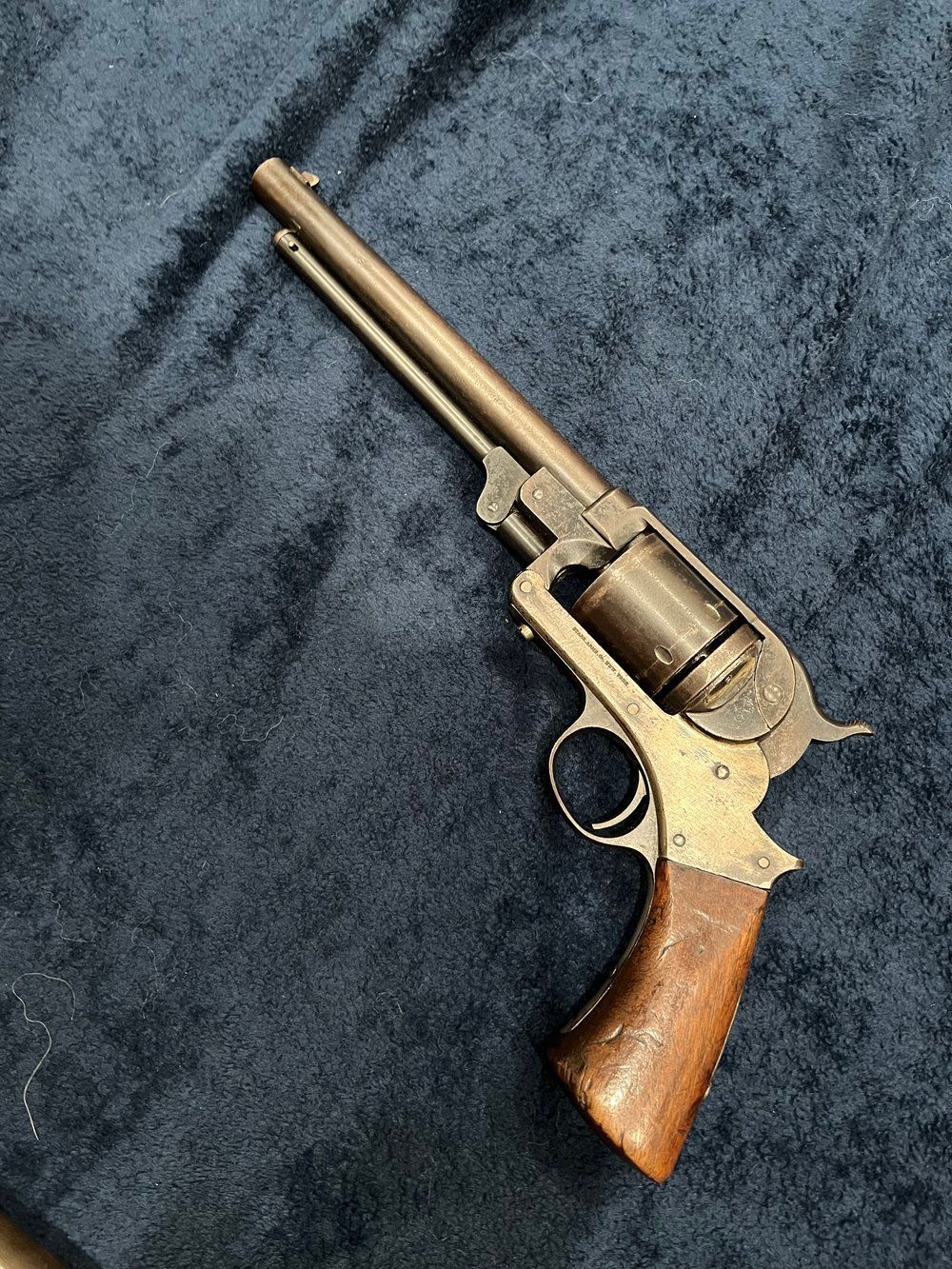 An old revolver with a wooden grip is sitting on a blue cloth.