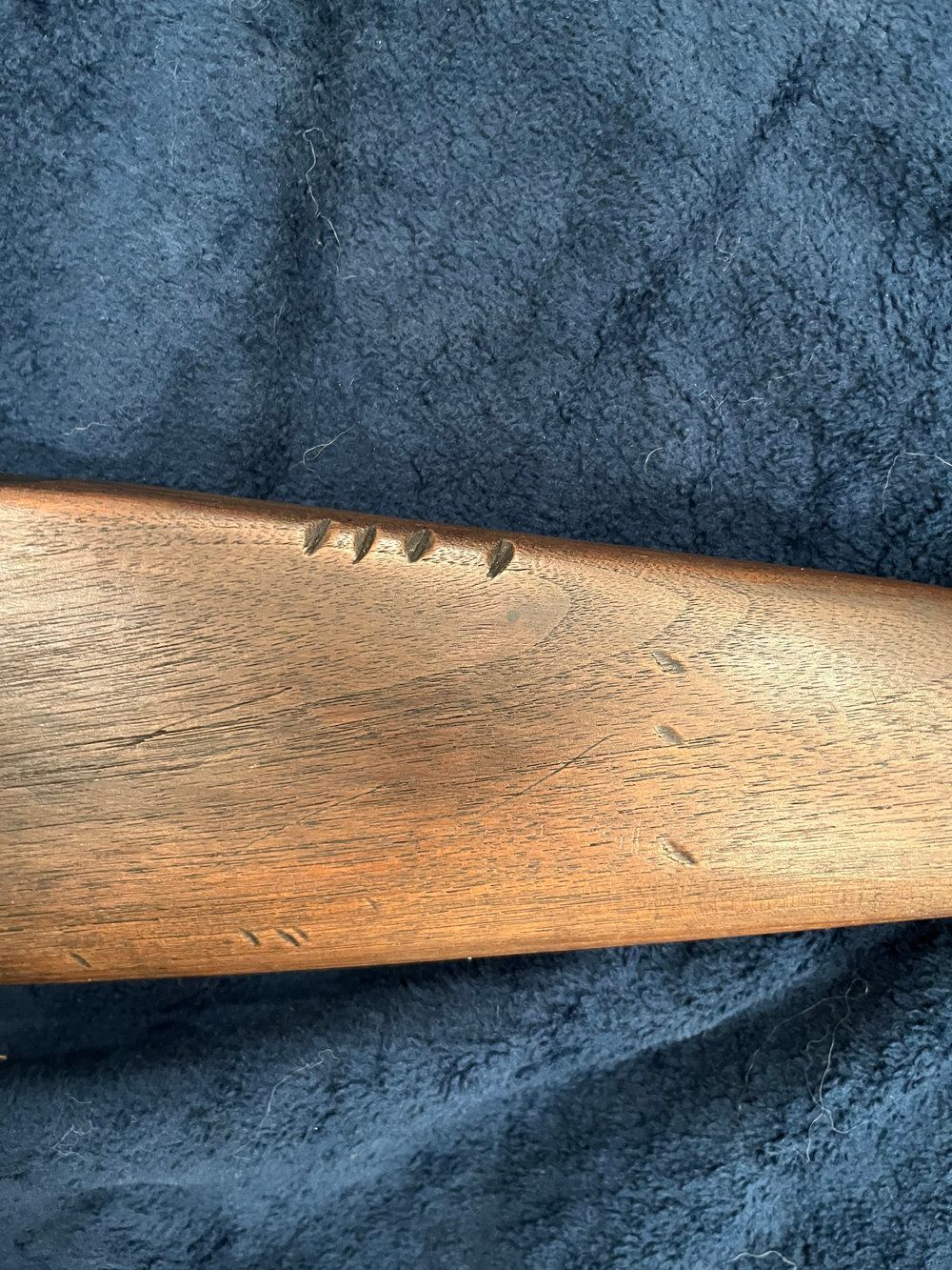 Lever-action rifle with wooden stock and metal components, laid on a dark blue textured surface.