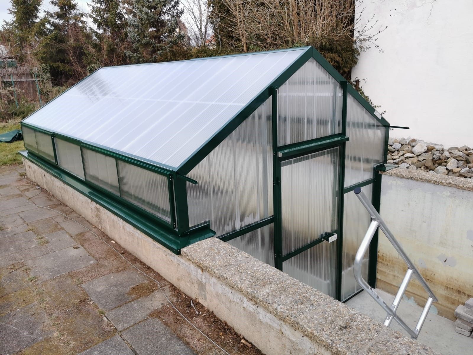 Gewächshaus auf Pool aufgebaut. Stirnseite im Pool bis Beckenboden. 