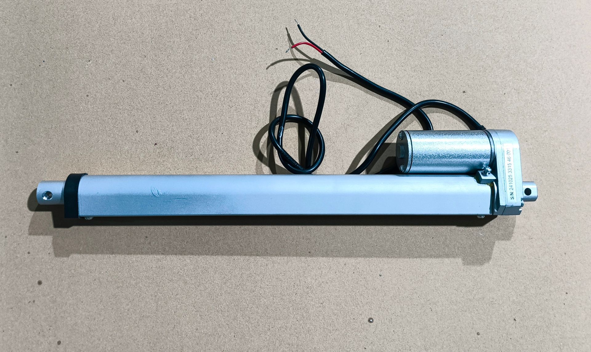 Silberner Linearantrieb mit angeschlossenem Motor und Kabeln auf neutraler Oberfläche.