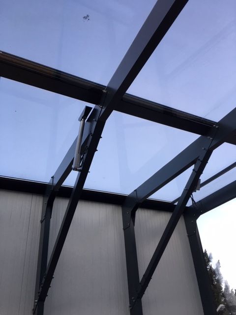 Silberner Linearantrieb mit schwarzen Drähten und Motor auf brauner Oberfläche.